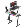 Gejmerski sto Huzaro Hero 6.0 iz leve zadnje perspektive sa tabletom, šoljom kafe i nosačem za slušalice i džojstike, uz RGB LED osvetljenje.